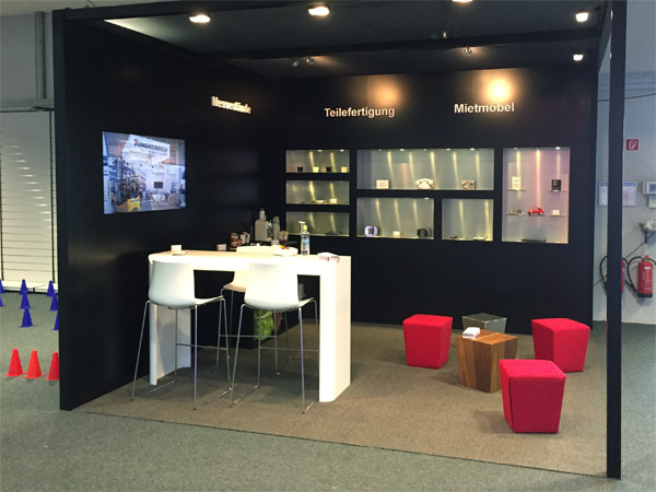 Messestand mit Einbauregalen, Brckentisch, Loungehocker, Beleuchtung
gefrsten Logos und eingebautem Display